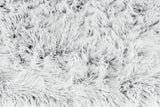 Flauschige, weiße Oberfläche mit dichtem, langem Flor aus weichem Material in unregelmäßigen Mustern.