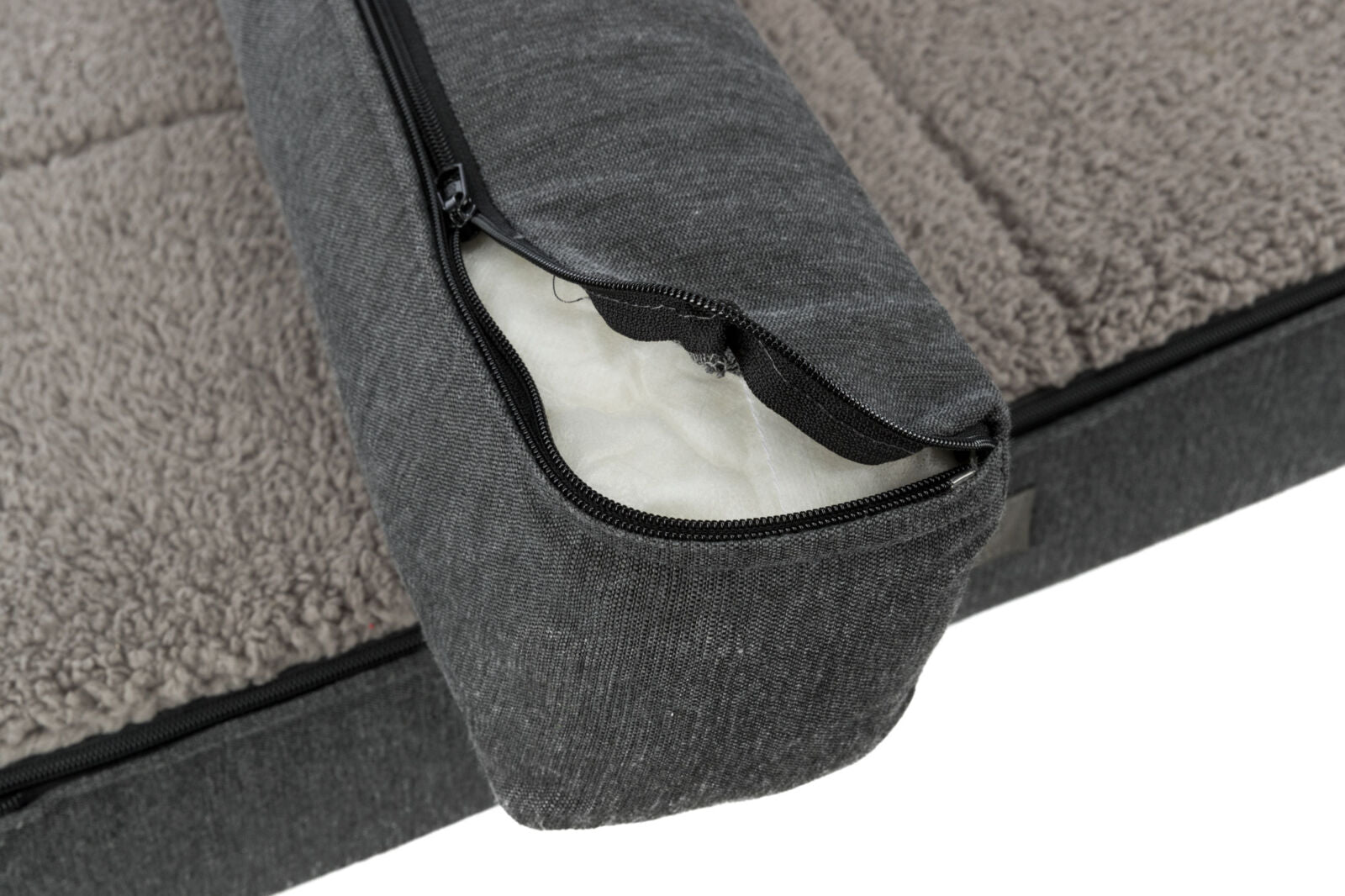 Graues Hundebett mit abnehmbarem Bezug, offenen Reisverschluss zeigend, und flauschiger, beige-weißer Oberfläche.
