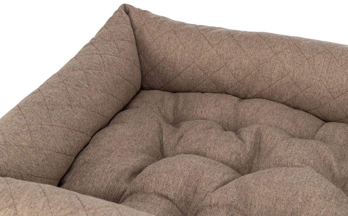 Beiges, gesteppte Kissen mit weicher, gepolsterter Oberfläche in einer Ecke angeordnet.