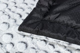 Nahaufnahme von zwei Materialien: Einem grauen, flauschigen Stoff mit runden Mustern und einem schwarzen, punktierten Stoff.