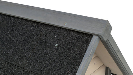 Schwarzes, grobkörniges Dachmaterial mit grau gestrichenem Holzrahmen, Detailaufnahme einer Konstruktionsektion.