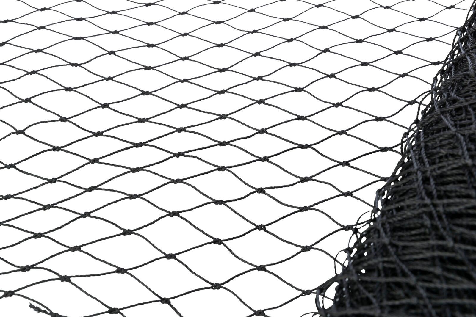 Schwarzes Netz mit quadratischen Maschen liegt auf einer weißen Fläche, ein Teil des Netzes ist zusammengerollt.
