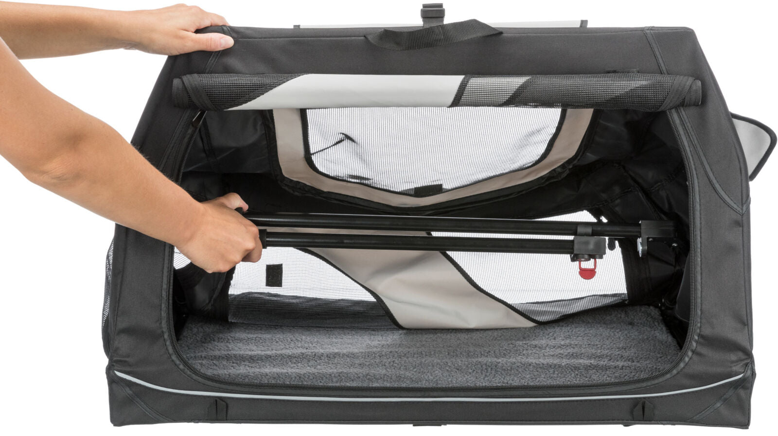 Schwarze Transportbox mit Netzfenster und grauem Innenraum, eine Hand justiert den seitlichen Rahmen.