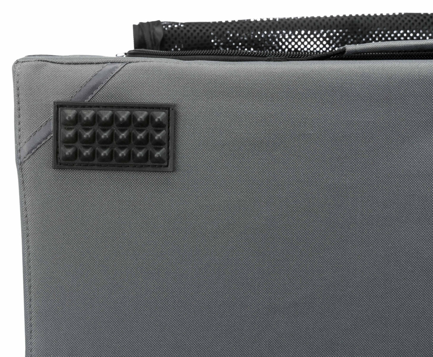 Graues Textilmaterial mit rechteckigem, genopptem, schwarzen Aufnäher und schwarzer Netztasche oben.