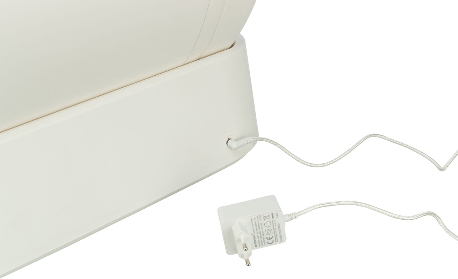 Ein weißes elektrisches Gerät ist mit einem Netzkabel verbunden, das in eine Steckdose eingesteckt wird.