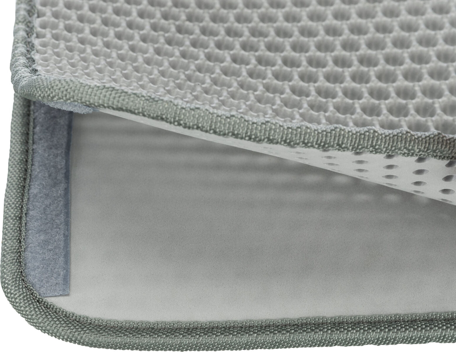 Graue rechteckige Matte mit wabenförmiger Textur und grüner Umrandung, teilweise zur Seite gefaltet.