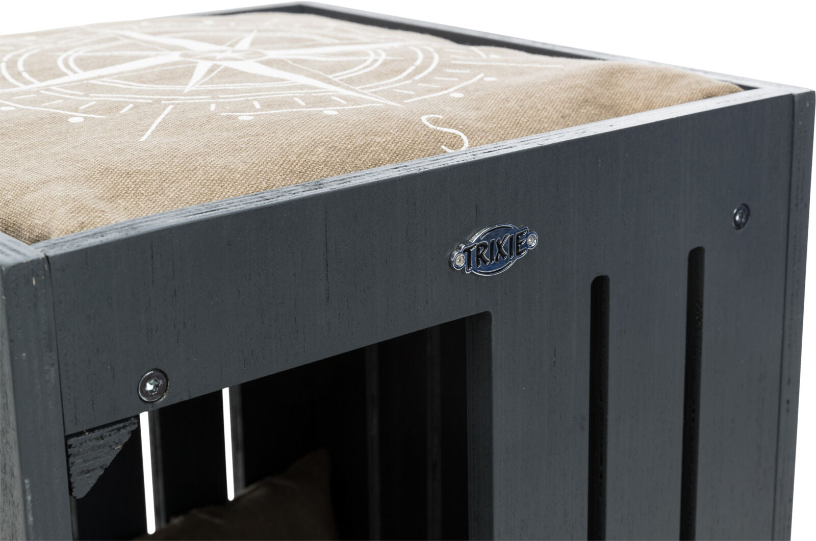 Graue Holzkiste mit beigem Kissen und Kompassmuster, darauf ein Trixie-Label, sichtbare Schrauben.