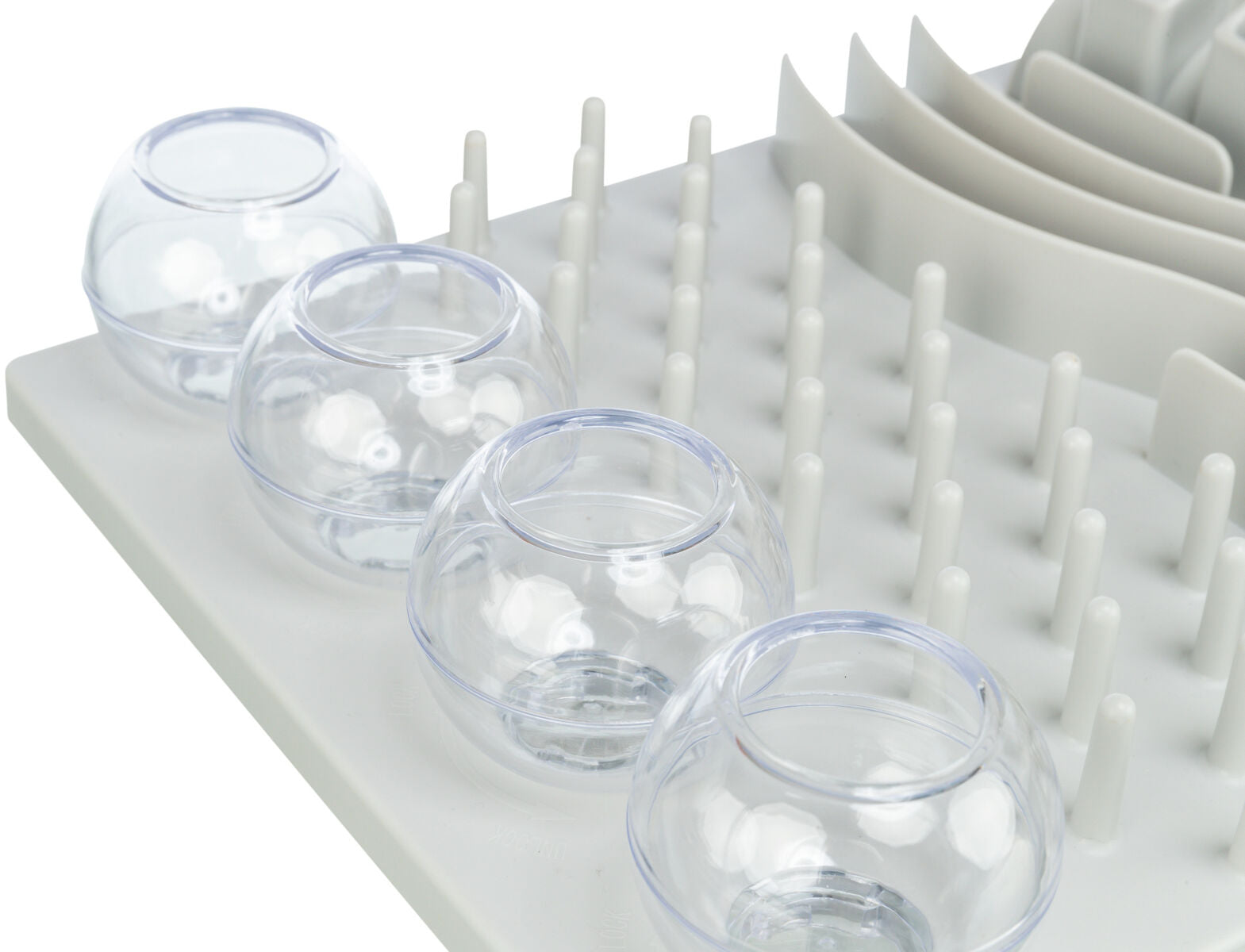 Transparente, kugelförmige Behälter stehen auf grauer Fläche mit weißen Stiften und gebogenen Elementen.