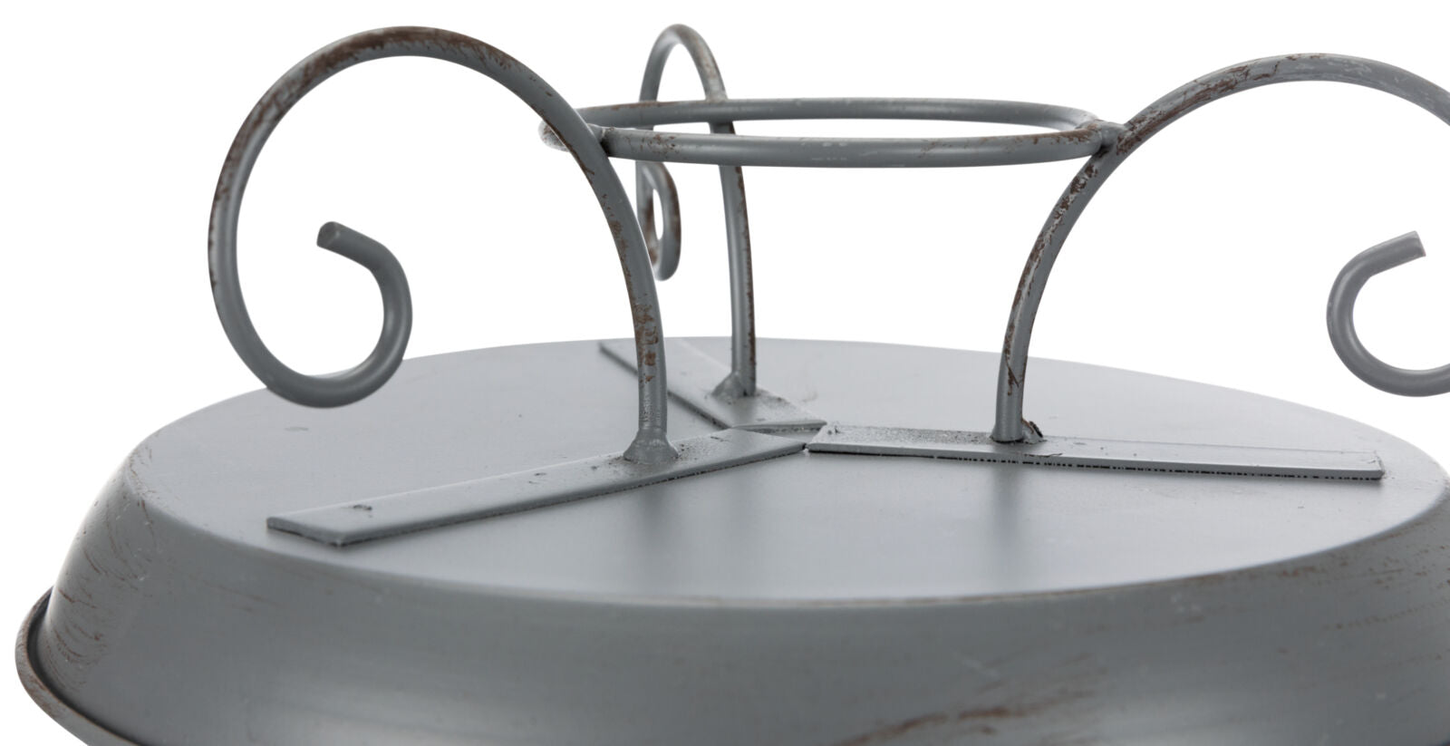 Metallisches, graues, rundes Objekt mit gewundenen Verzierungen und mehreren rostigen Stellen auf der Oberfläche.