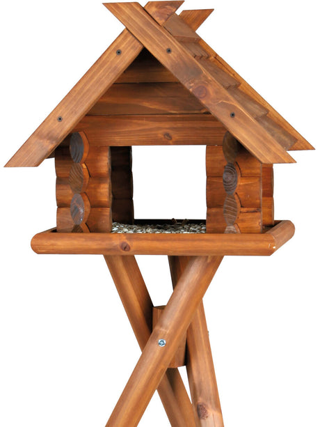 Holzfarbenes Vogelhaus mit Satteldach auf einem stabilen, gekreuzten Standfuß.