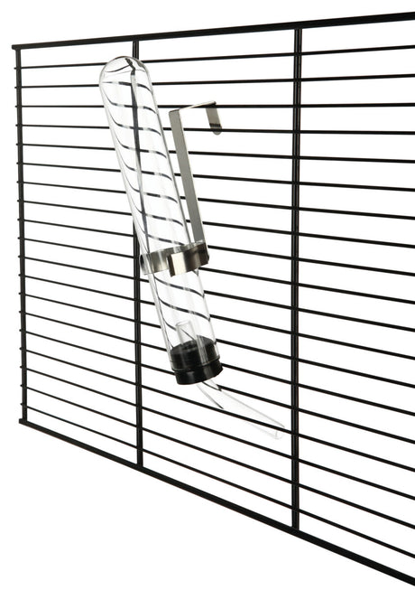 Ein transparentes Trinkfläschchen mit Metallhalterung ist an einem schwarzen Gitter befestigt.