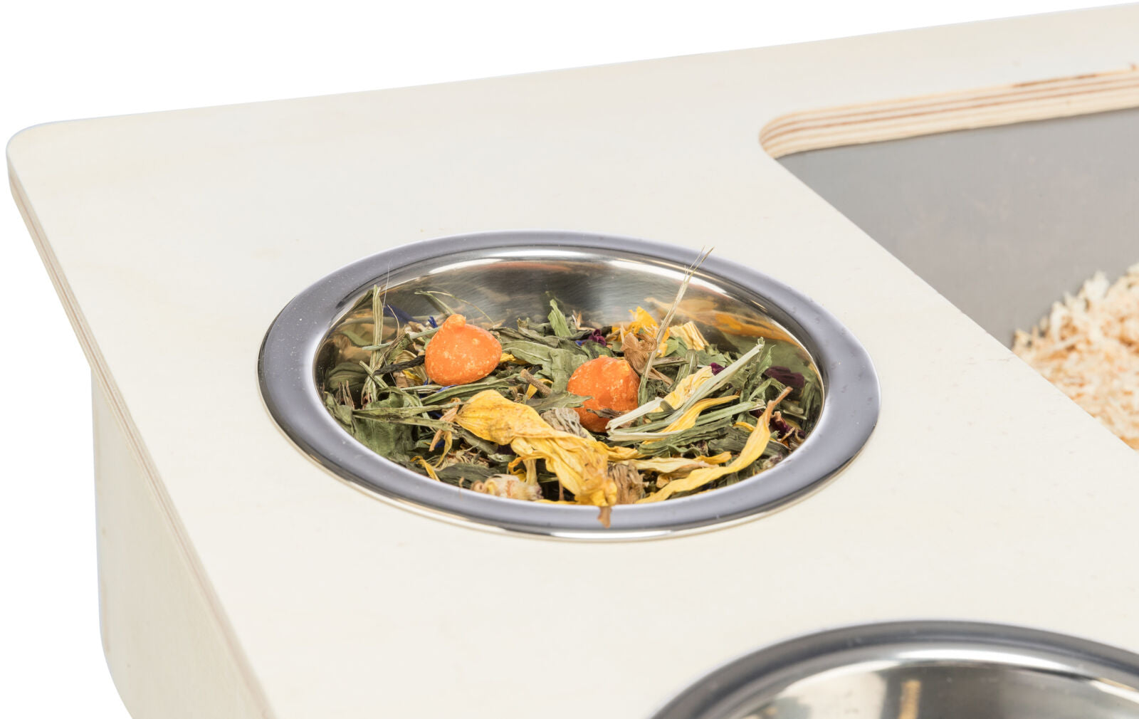 Silberner Napf mit getrockneten Pflanzen und Karottenscheiben auf Holzplatte.