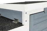 Nahaufnahme einer Ecke eines Holzkonstrukts mit blauer Wand, weißem Rahmen, schwarzen Dachplatten und silbernen Scharnieren.
