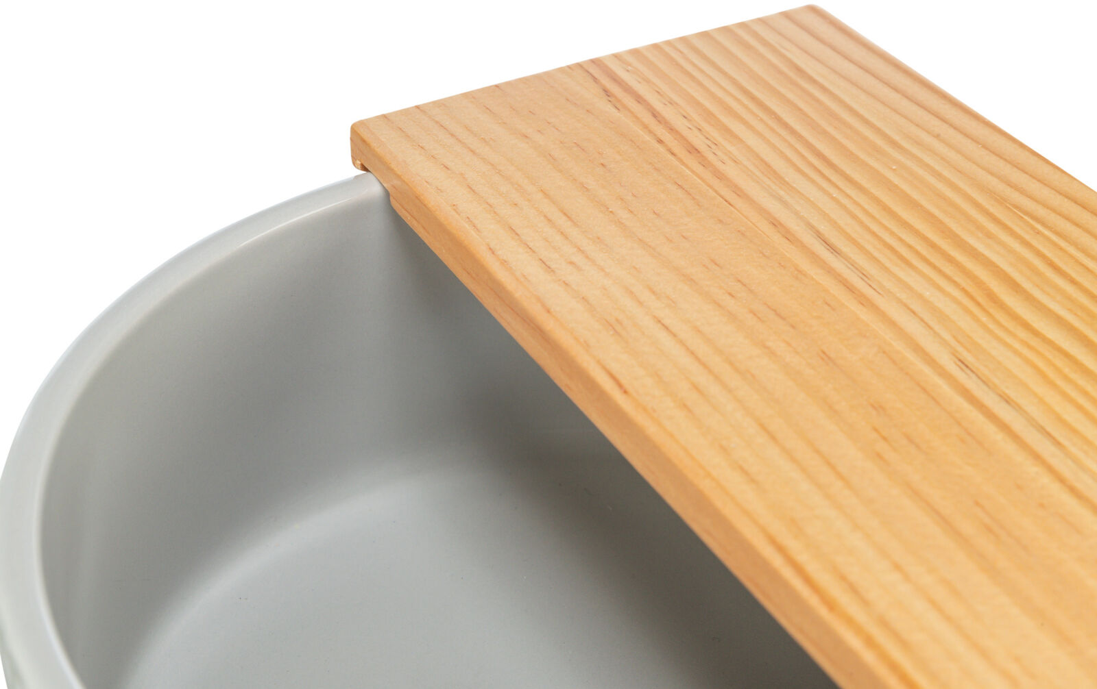 Graue runde Schale mit hölzerner Abdeckung, die teilweise die Schale überdeckt.