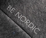 Grauer Textilstoff mit der Aufschrift "BE NORDIC" in weißen Buchstaben.