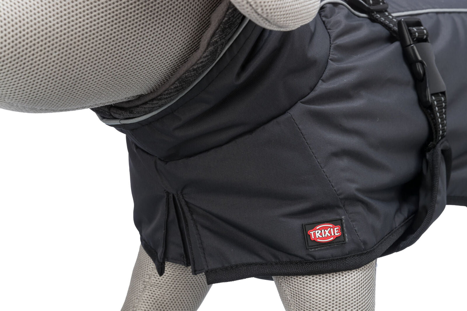 Grauer Hundemantel auf einer Stoffpuppe mit schwarzem Verschluss und rotem Logo, bestehend aus glattem Material.