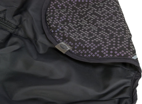 Schwarzer Stoff mit geometrischem Muster in Lila und Grau, Label mit "TRIXIE"-Schriftzug sichtbar.
