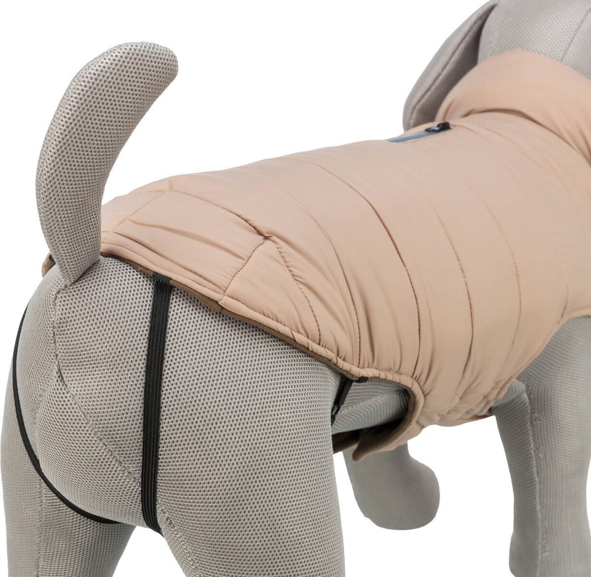 Hundemantel in Beige auf grauer Stoffpuppe mit schwarzem Gummizug an den Beinen befestigt.