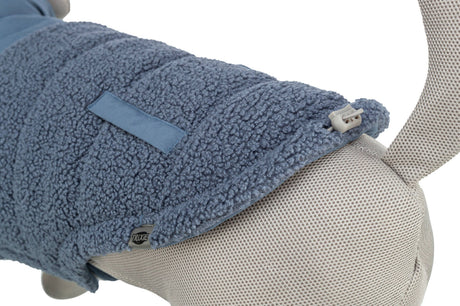 Blaues, texturiertes Material über beige Netzstoff mit Clipverschluss und einem kleinen Etikett.