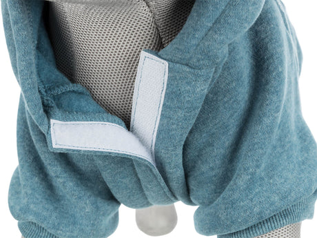 Grauer Stoff über einem Objekt mit sichtbarem, blauem Kleidungsstück und Klettverschluss.