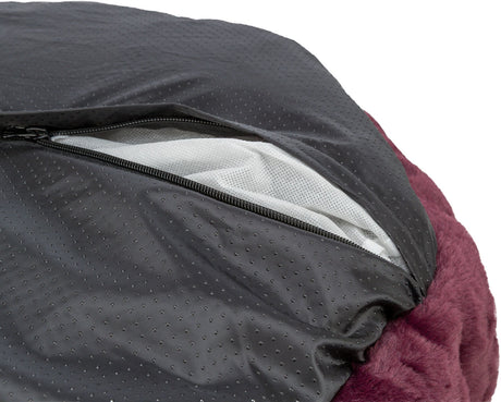 Ein geöffneter Reißverschluss in einem schwarzen, gepunkteten Stoff über einem weichen, bordeauxfarbenen Material.