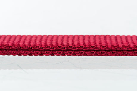 Rotes, flach gewebtes Band auf weißem Hintergrund in Nahaufnahme.