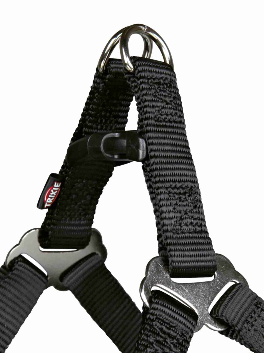 Schwarzes Hundegeschirr aus Nylon mit Metallringen und Verschluss, Etikett mit "Trixie" Schriftzug sichtbar.