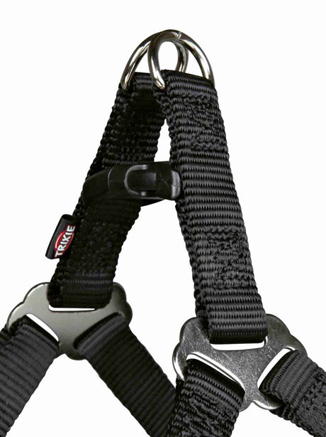 Schwarzes Hundegeschirr aus Nylon mit Metallringen und Verschluss, Etikett mit "Trixie" Schriftzug sichtbar.
