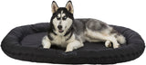 Hund mit schwarz-weißem Fell auf rundem, schwarzem Tierbett liegend.