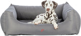 Ein Hund liegt in einem großen, grauen Hundebett mit dem Schriftzug "Samoa Vital" auf der Vorderseite.