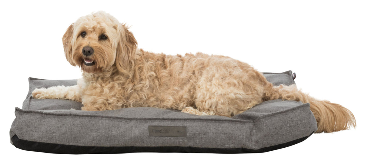 Ein beige-brauner Hund liegt auf einem grauen Hundebett mit sichtbarem "homeEdition Trixie"-Label.