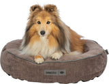 Brauner Hund sitzt auf einem runden, braunen Hunde-Bett mit weichem Rand und Etikett "homeEdition".