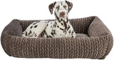 Ein gefleckter Hund liegt in einem braunen geflochtenen Hundebett.