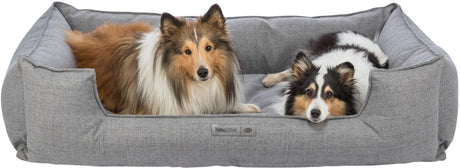 Zwei Hunde liegen entspannt in einem grauen Hundebett mit einem Etikett, das "homeEdition TRIXIE" zeigt.