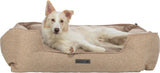 Ein Hund mit hellem Fell liegt entspannt in einem beigefarbenen Hundebett, auf dem Etikett steht "homeEdition".