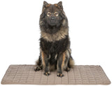 Ein großer, flauschiger Hund sitzt auf einer rechteckigen, gesteppten, beigen Matte vor weißem Hintergrund.