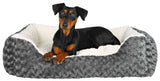 Ein schwarzer Hund liegt in einem grauen, plüschigen Bett mit weißem Innenfutter.