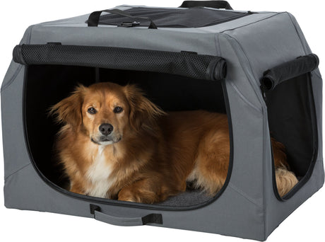 Ein brauner Hund liegt in einer grauen Transportbox mit offenen Netzseiten und blickt aus dem Eingang.