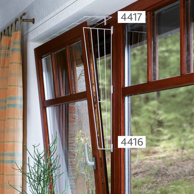 Braunes Fenster mit gekipptem Flügel, daran ein fest montiertes, weißes Gitter; Nummern 4416 und 4417 sichtbar.