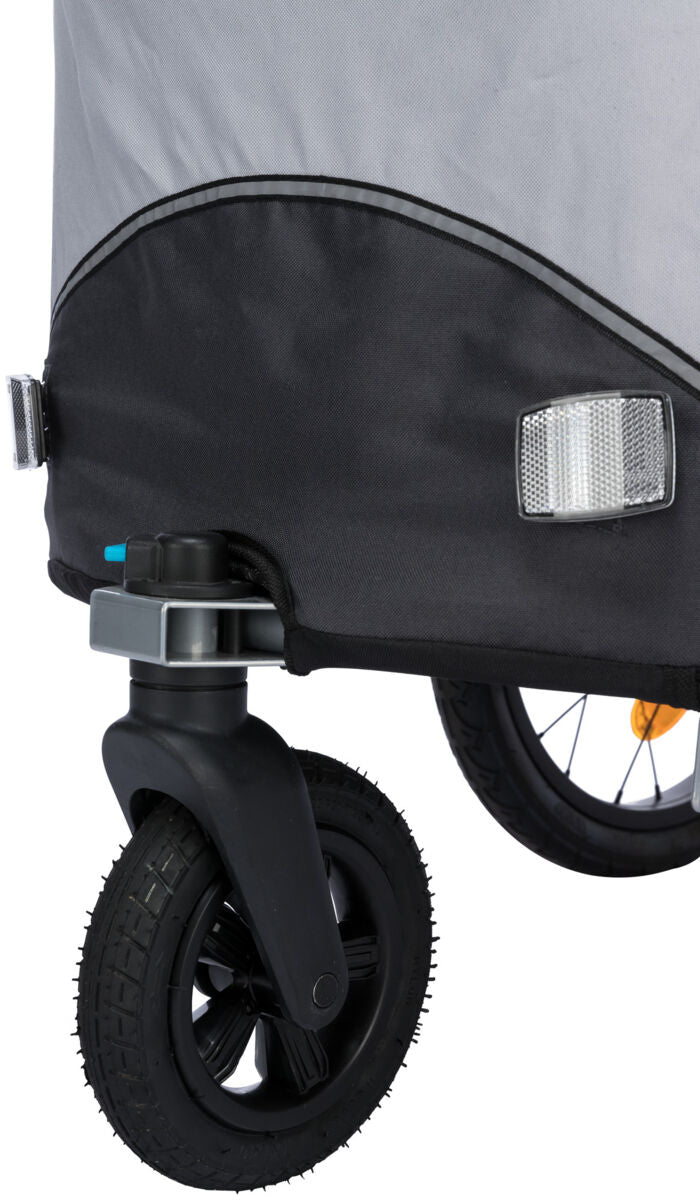 Teil eines Fahrradanhängers mit schwarzem Rad, Reflektoren und grauem Stoff.