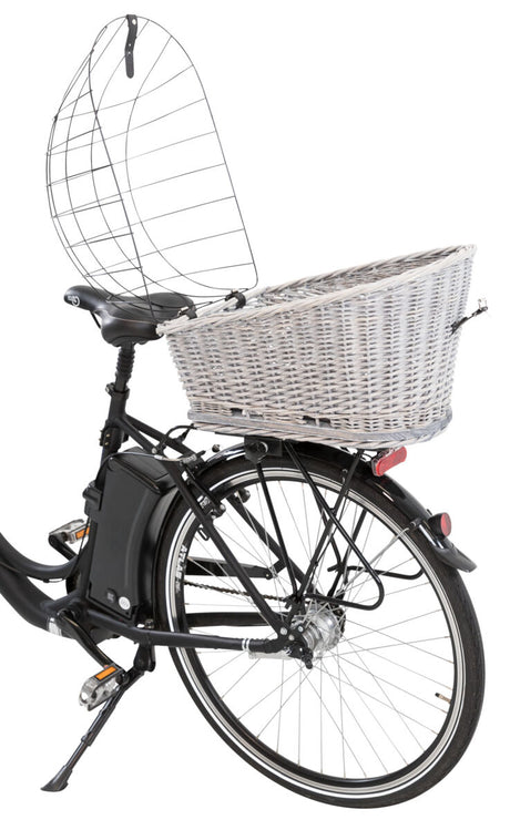 Fahrrad mit Korb hinten und einem Drahtschutz, der Korb ist aus hellem Geflecht, das Fahrrad hat schwarze Reifen.