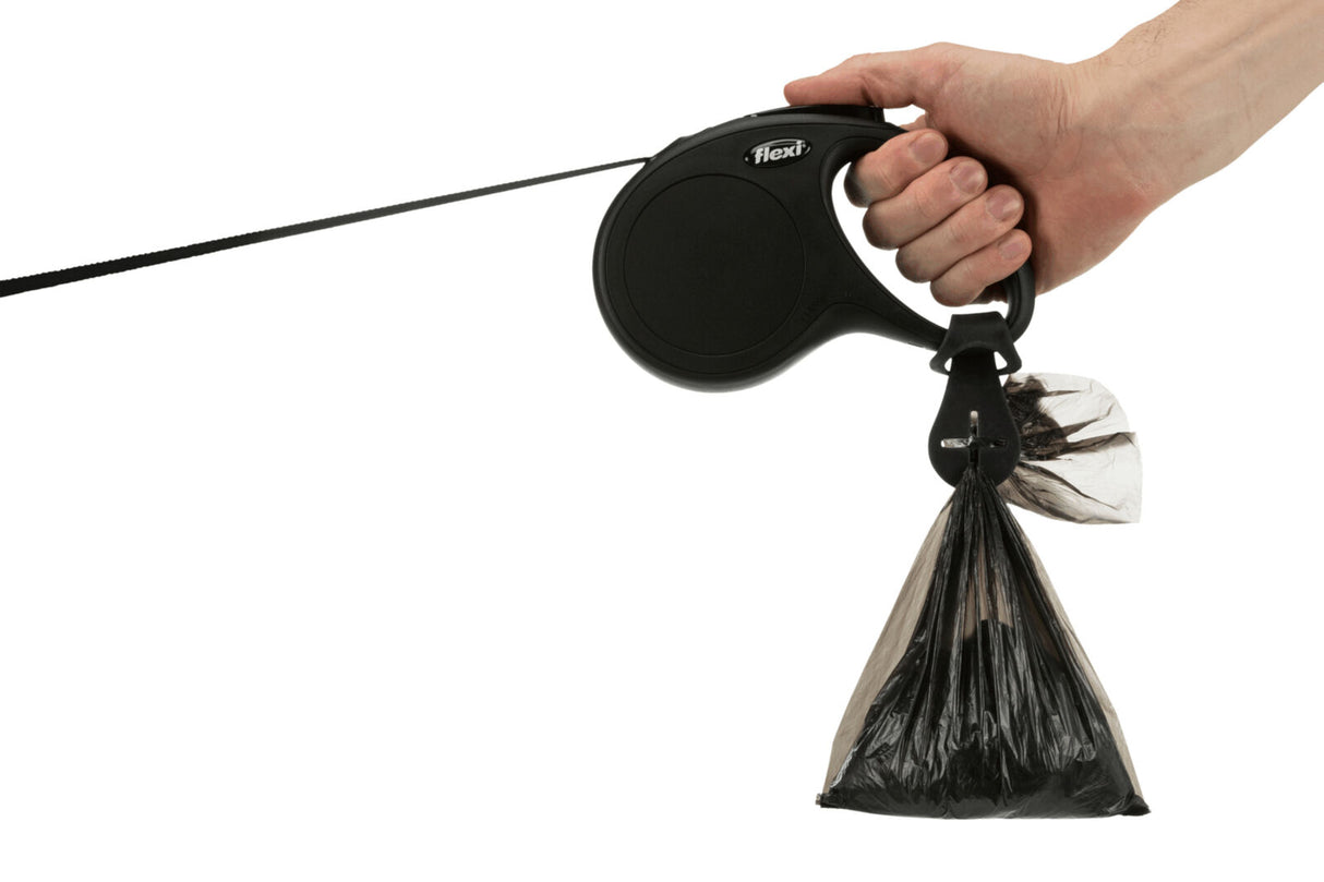 Eine Hand hält eine schwarze Hundeleine mit einem befestigten, schwarzen Abfallbeutel.