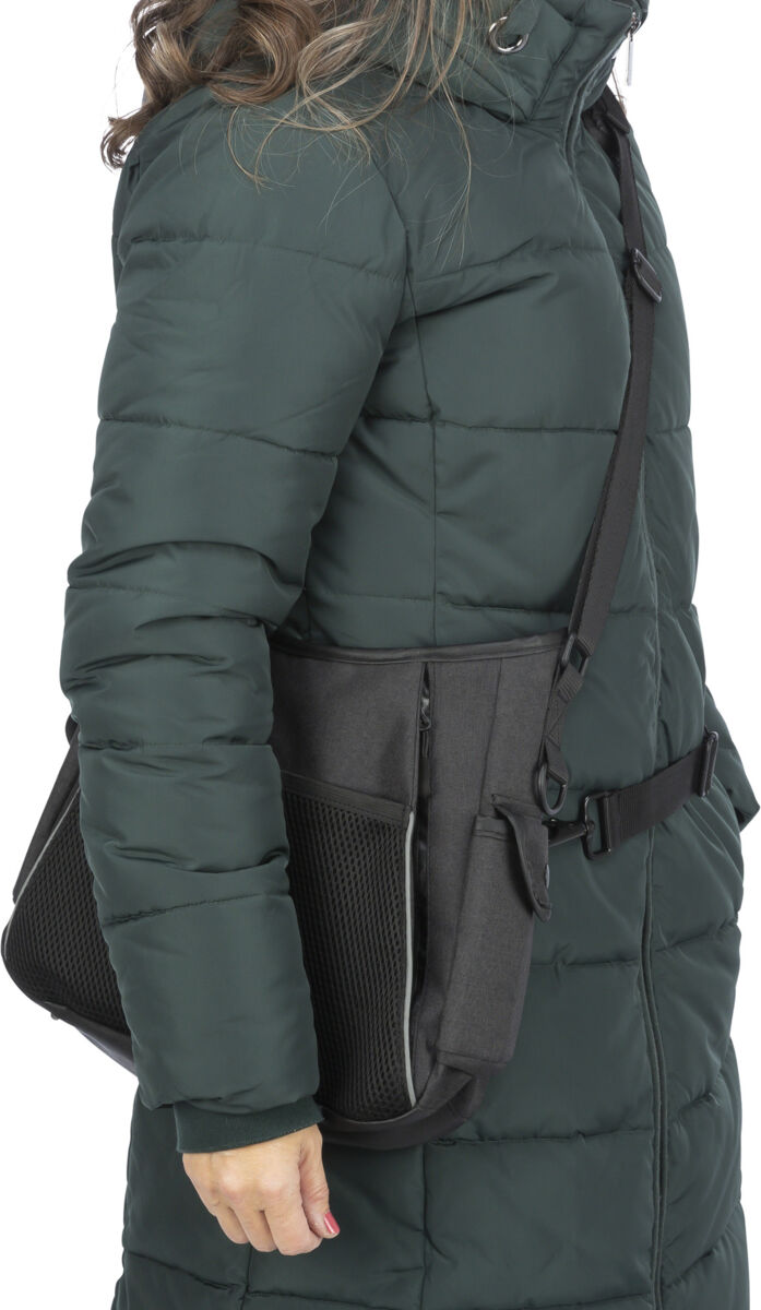 Person in dunkelgrünem gesteppten Mantel trägt schwarze Tasche mit Gurt über der Schulter.