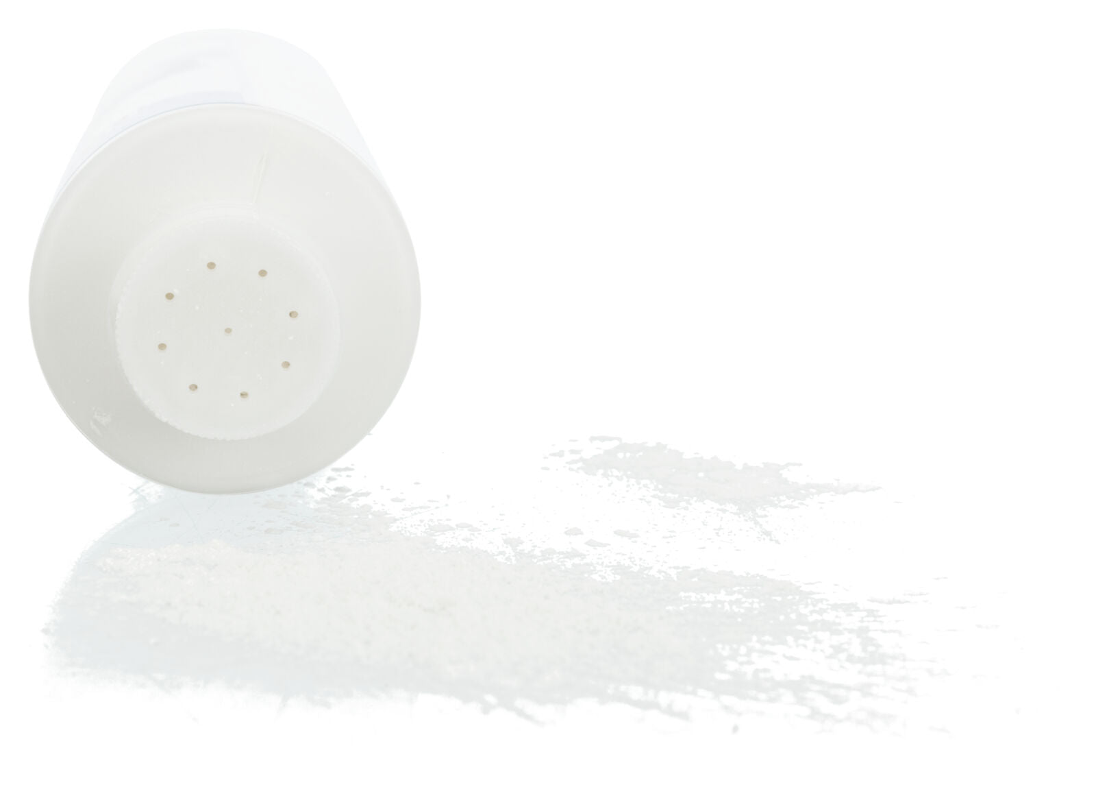 Ein umgefallener weißer Streuer mit kleinen Löchern verteilt feines weißes Pulver auf einer glatten Oberfläche.