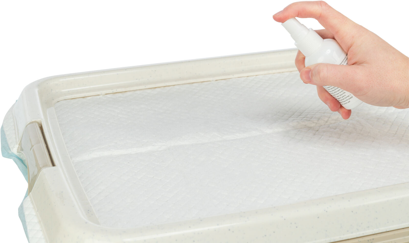 Hand hält eine weiße Sprühflasche über ein weißes Polster auf einem rechteckigen Tablett.