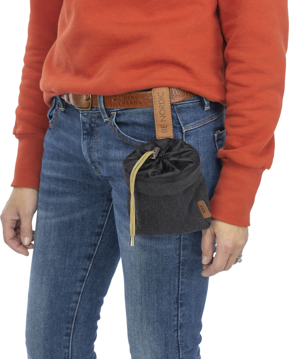 Person trägt orangefarbenen Pullover und blaue Jeans, eine schwarze Tasche mit Kordelzug ist an einem braunen Gürtel befestigt.