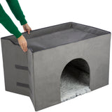 Grauer, rechteckiger Höhlenwürfel mit gewölbtem Eingang und weicher, heller Innenfläche, Person hält ihn oben.