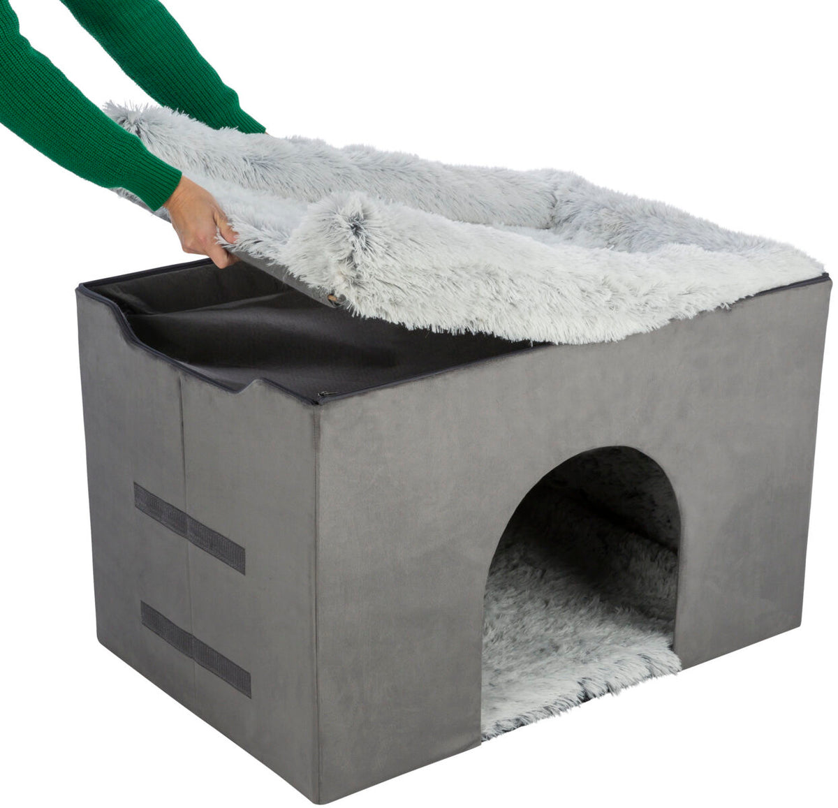 Graue, würfelförmige Höhle mit weichem, abnehmbarem Bezug, Hand hebt obere Abdeckung an.