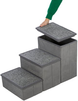 Graue, dreistufige Treppe mit abnehmbaren Deckeln, die eine Person mit grünem Ärmel öffnet.